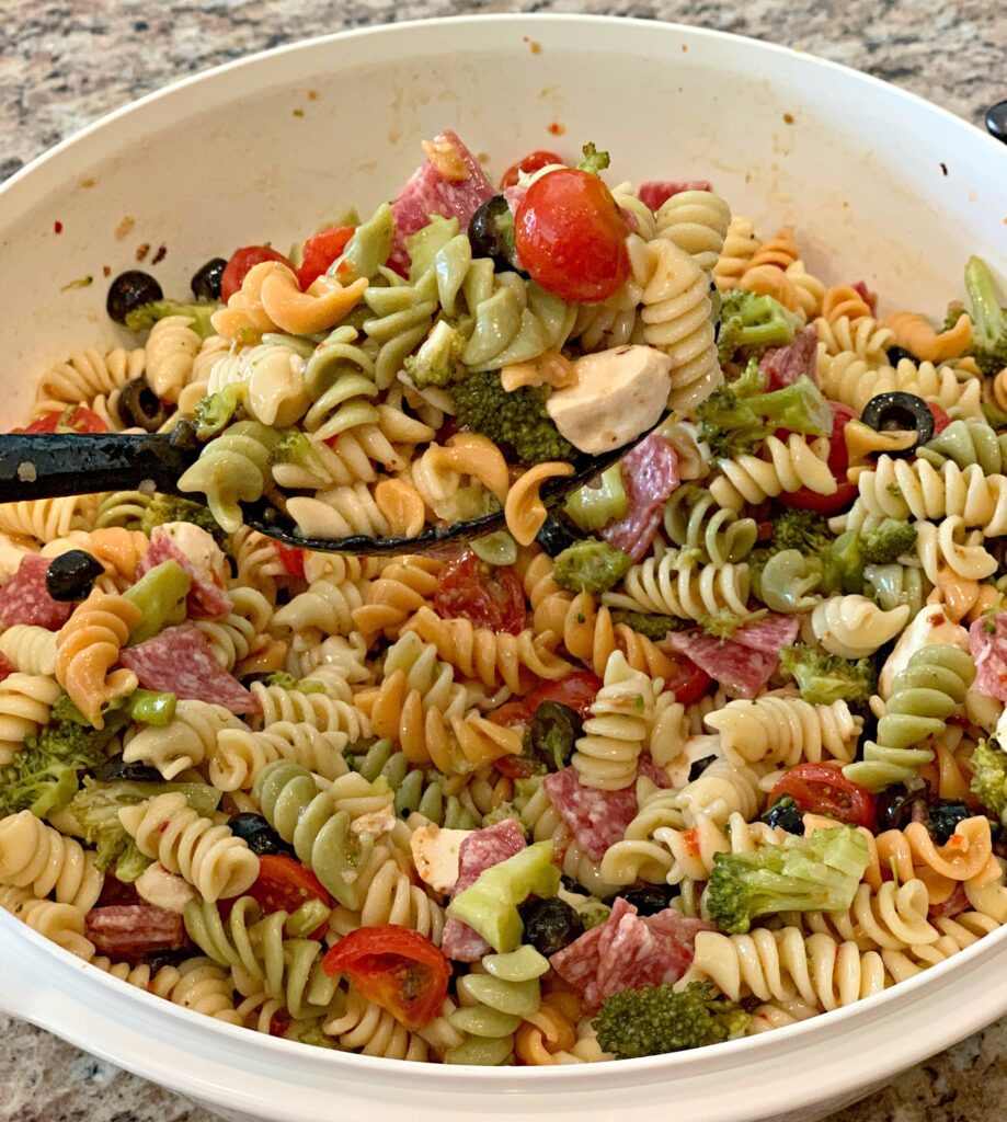 tender pasta coated in dressing and added tomatoes, broccoli, cheeses, and veggies