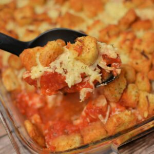 a spoon taking a scoop out of baked chicken parmesan casserole.