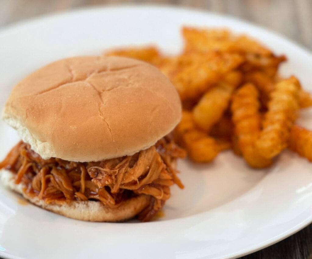 slow cooker bbq chicken served on a hamburger bun with fries
