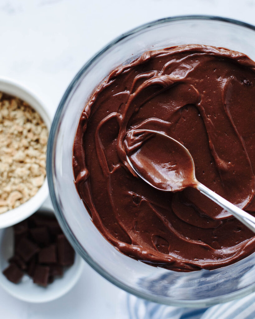chocolate pudding spread on top of chocolate cake in a glass bowl.