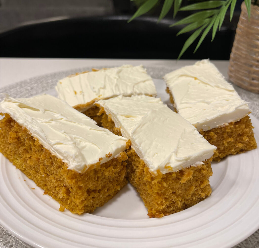 pumpkin cake cut into bars and topped with cream cheese frosting