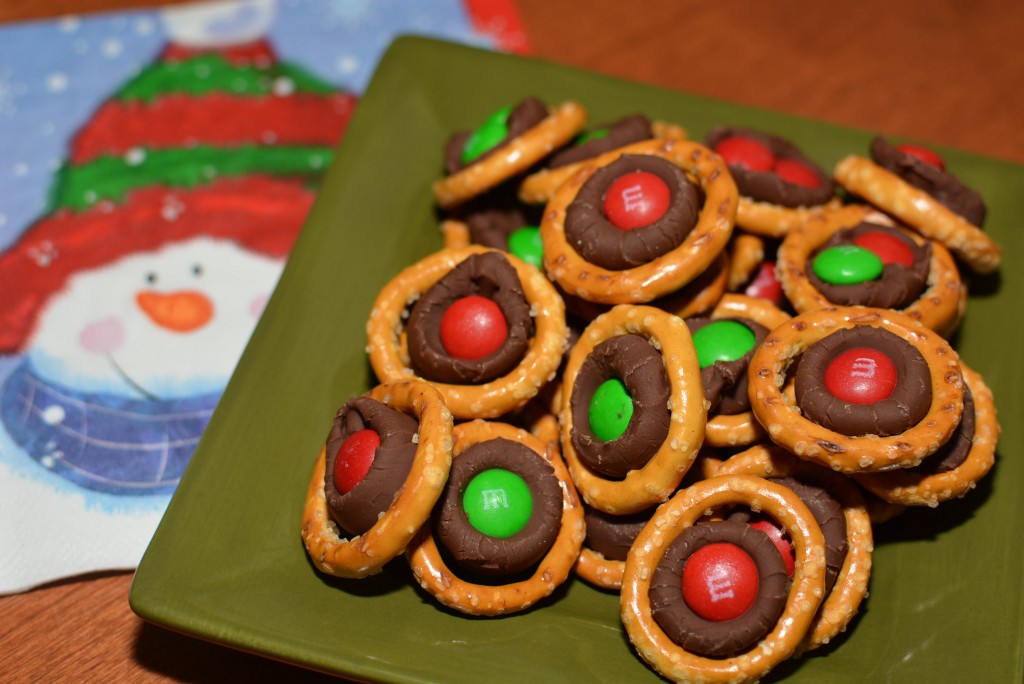 hershey kisses melted in the center of a pretzel with an m & m placed on top for a christmas chocolate treat