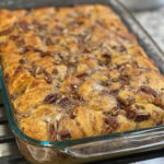 cinnamon roll pieces baked into a casserole with syrup and pecans
