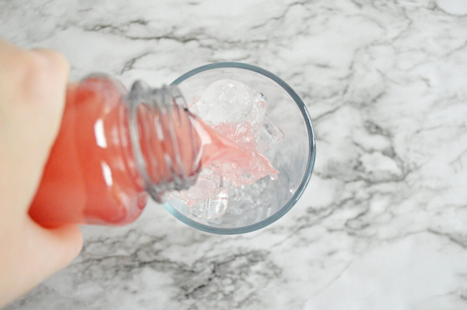 pink lemonade poured over ice in a glass.