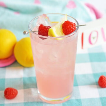 A refreshing glass of Malibu and pink lemonade cocktail garnished with lemon and fresh berries