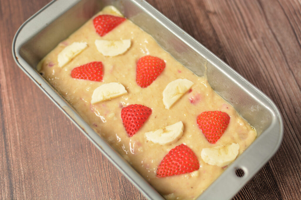 fresh strawberries and banana slices on top of quick bread batter
