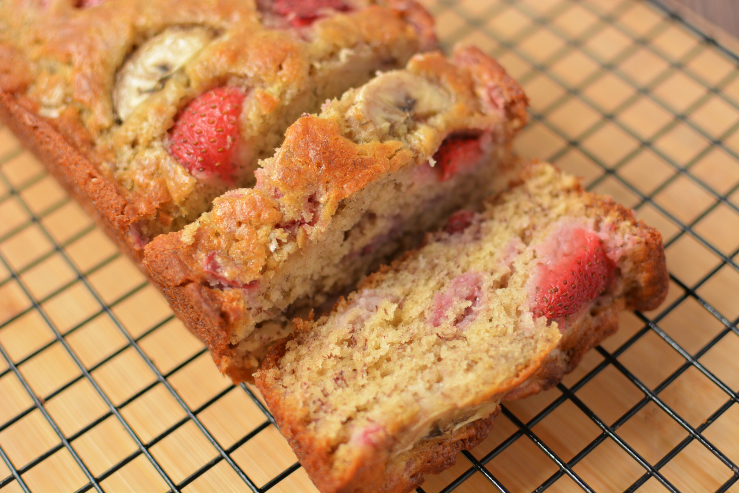 slices of strawberry banana bread on a cooling rack.