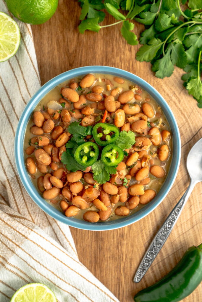 authentic Mexican beans served in a bowl with jalapeno slices on top.