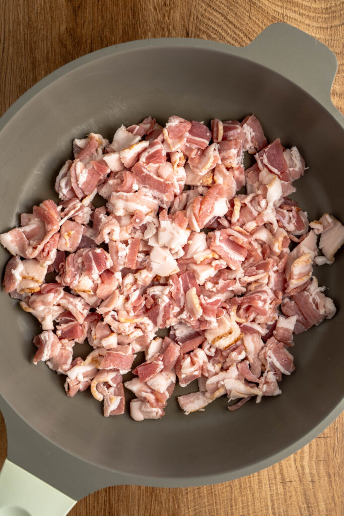 bacon being cooked in a skillet.