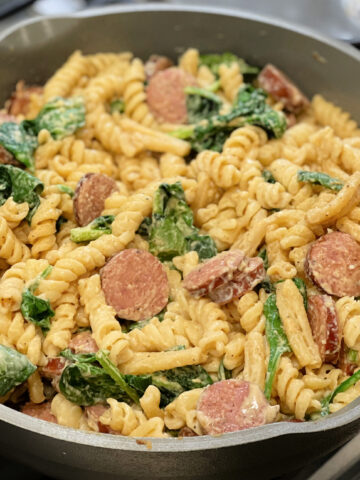 cajun seasoned alfredo pasta with spinach and sausage slices throughout