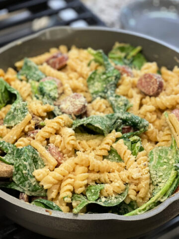cajun seasoned pasta covered in an alfredo sauce with sausage slices throughout