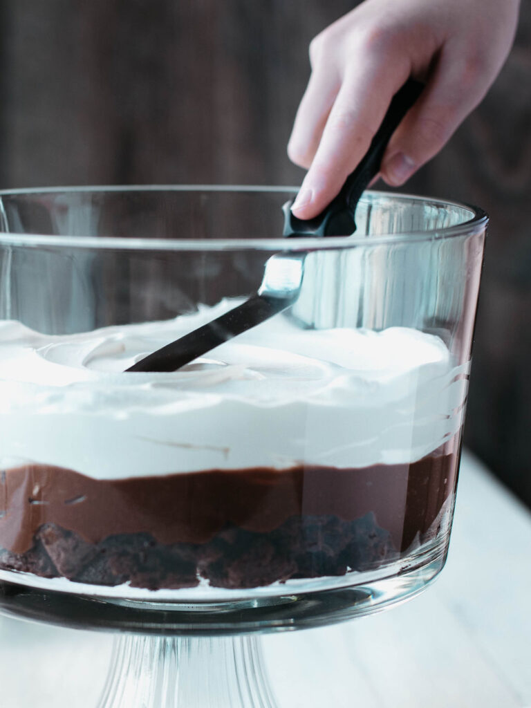 spreading cool whip into a trifle bowl.