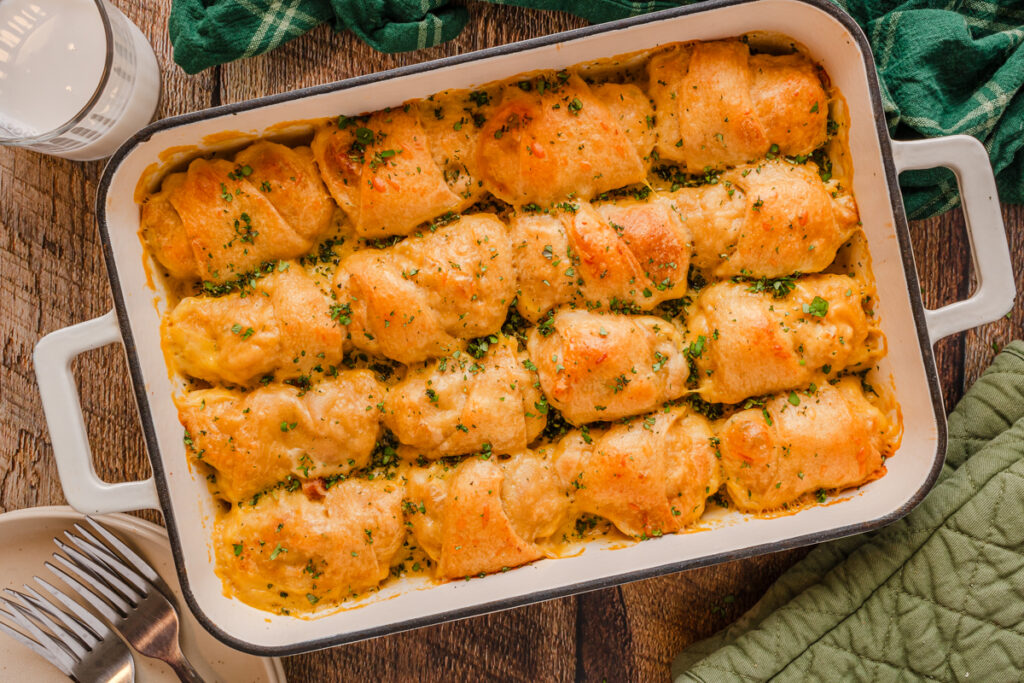 cheesy chicken crescent rolls lined up in a casserole dish.
