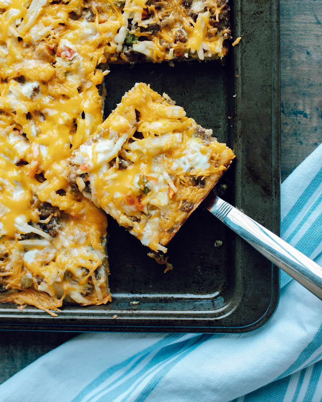 breakfast pizza being served from a cookie sheet.