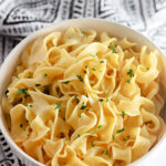 a white bowl with buttered Amish noodles.