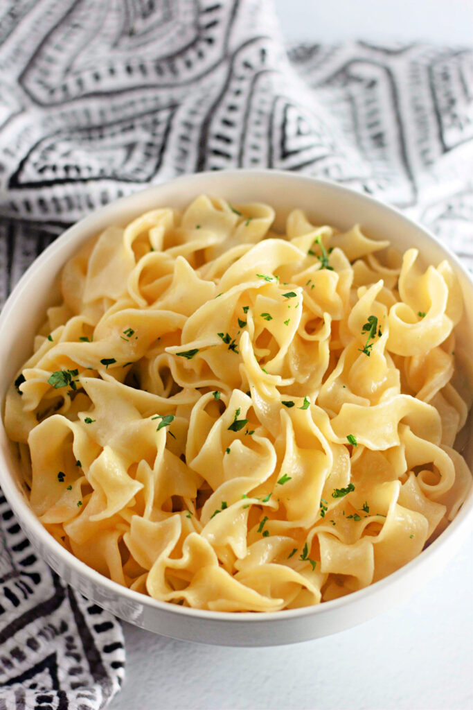 a white bowl with buttered Amish noodles.