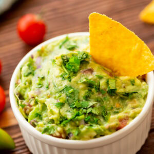 a small white bowl with homemade guacamole ready to serve with tortilla chips.