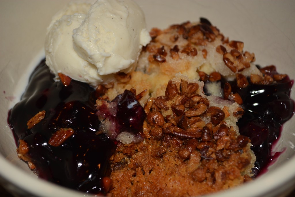 blueberry cobbler crisp served in a bowl with a scoop of vanilla ice-cream