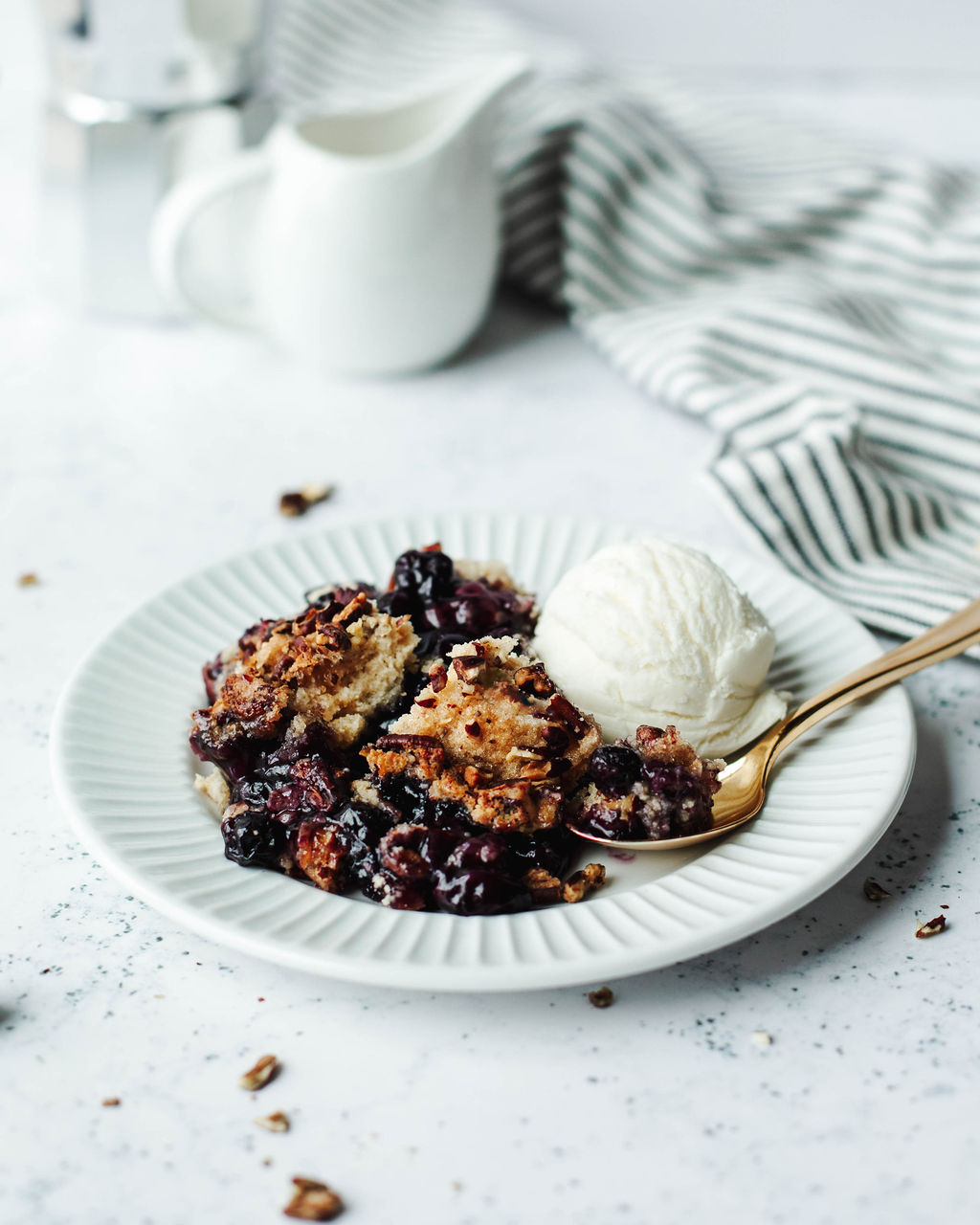 Scoop of blueberry cobbler with Bisquick topping served with vanilla ice cream.