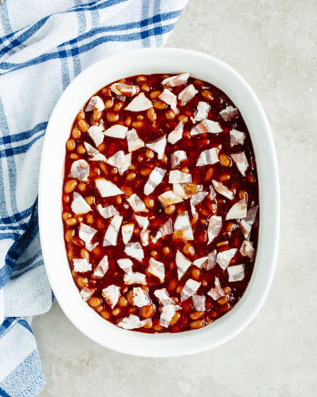 sliced bacon on top of a beans dish.