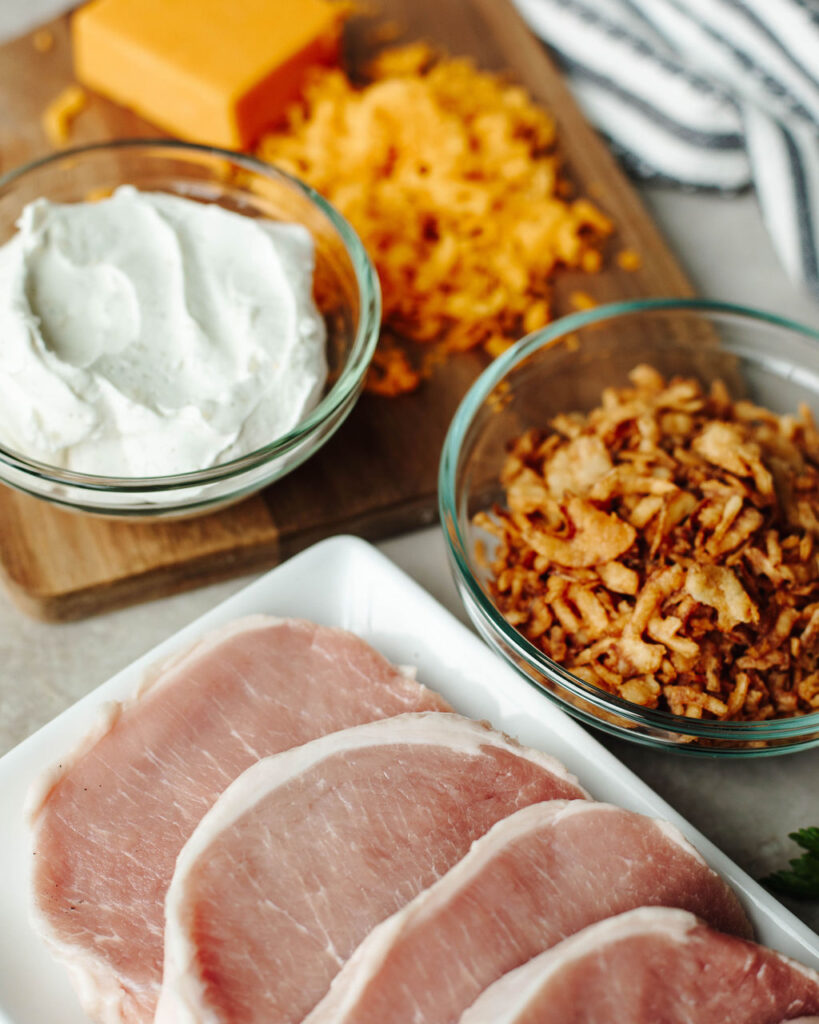 French Onion dip in a bowl with boneless pork chops and shredded cheese.