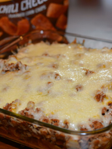 cheesy taco bake with layers of chips, beef, cheese, and seasoning