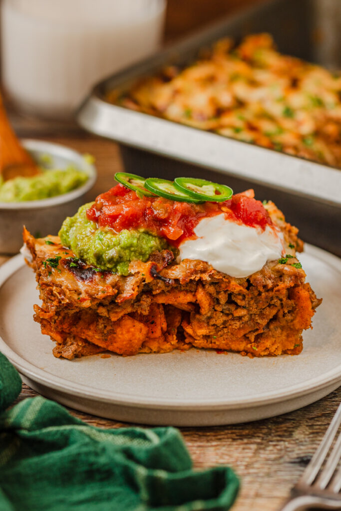 a side view of Frito Taco Casserole on a dinner plate with toppings.