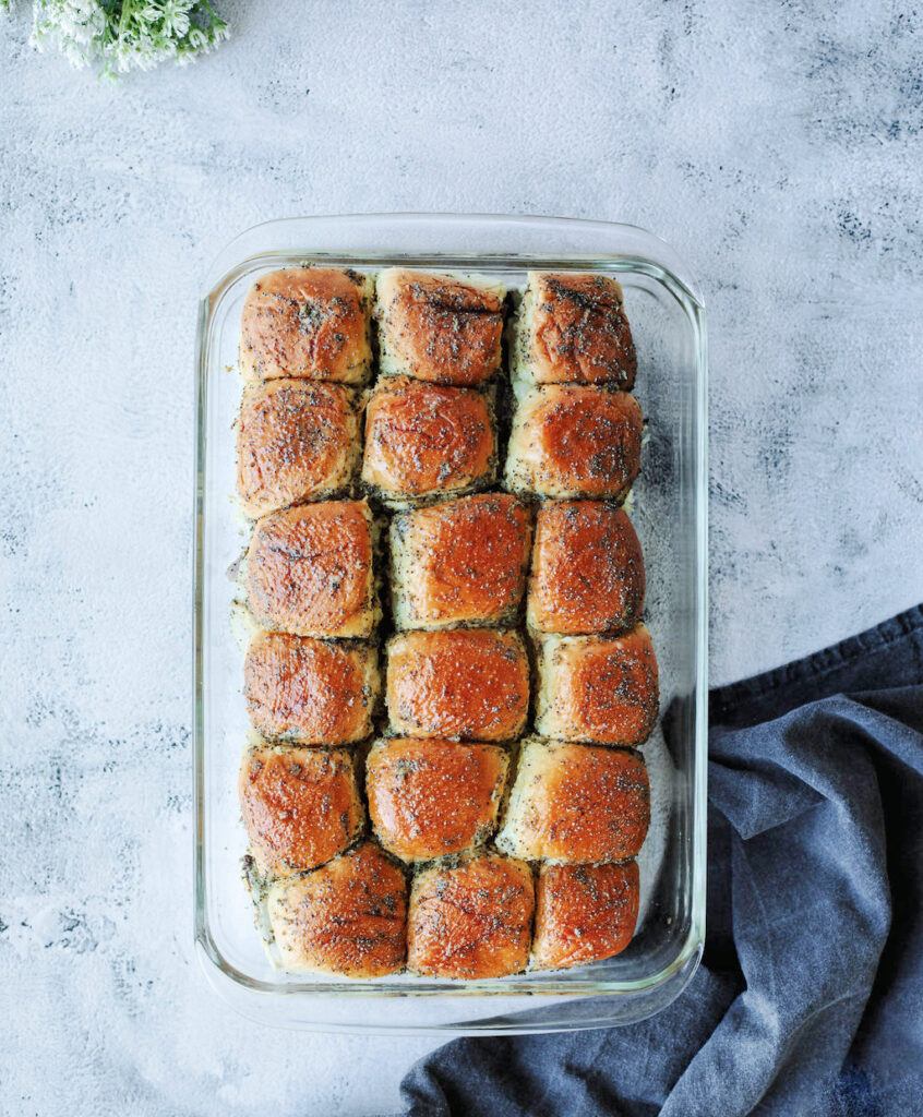 a 9x13 glass baking pan full of sandwiches fresh from the oven.