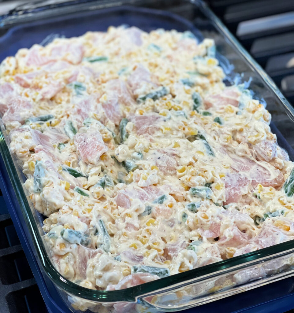 cut up chicken combined with sour cream, cream of chicken soup, seasonings, and vegetables in a pan