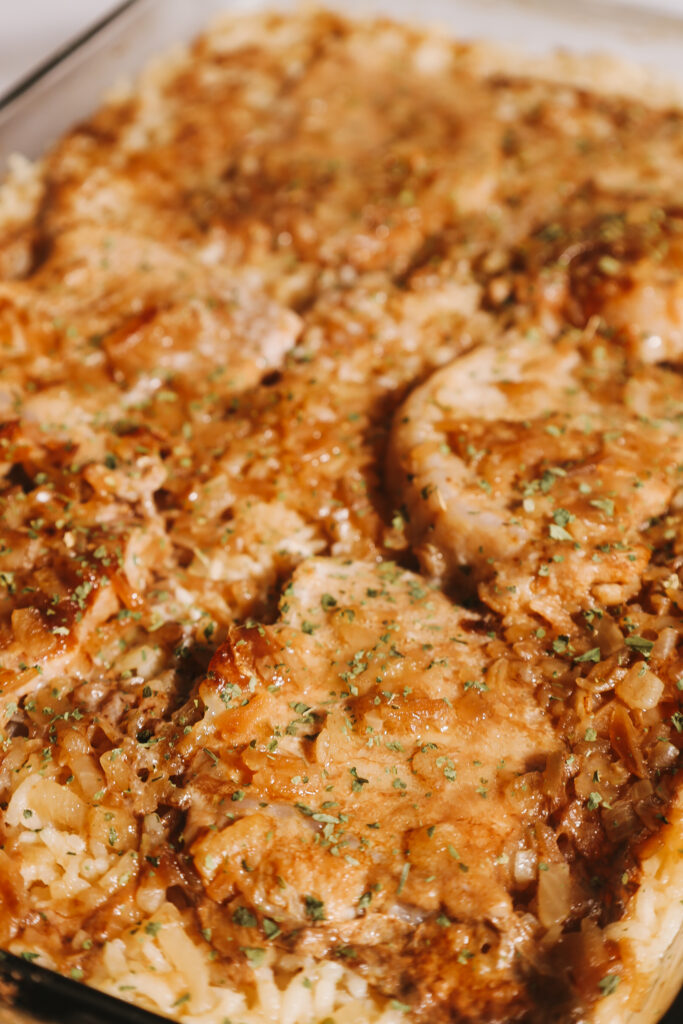 Um olhar de perto as costeletas de carne de porco cobertas de mistura de cebola e cozidas com arroz.