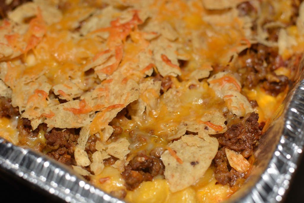 crushed tortilla chips on top of taco seasoned beef and macaroni and cheese