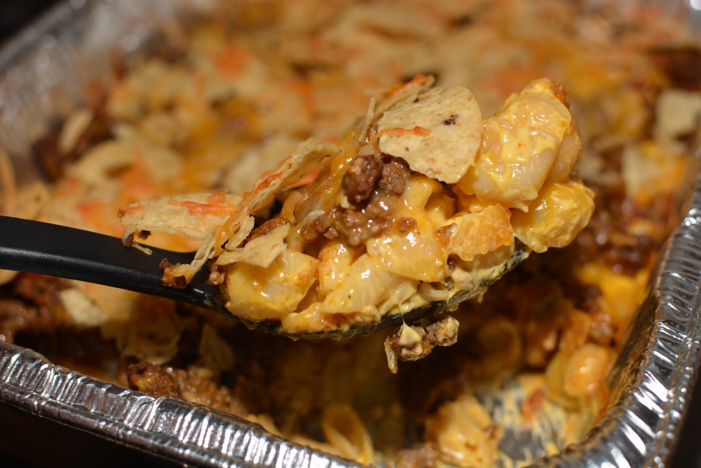 a cheesy nacho dish with macaroni and cheese, tortilla chips, salsa, cheese, and more