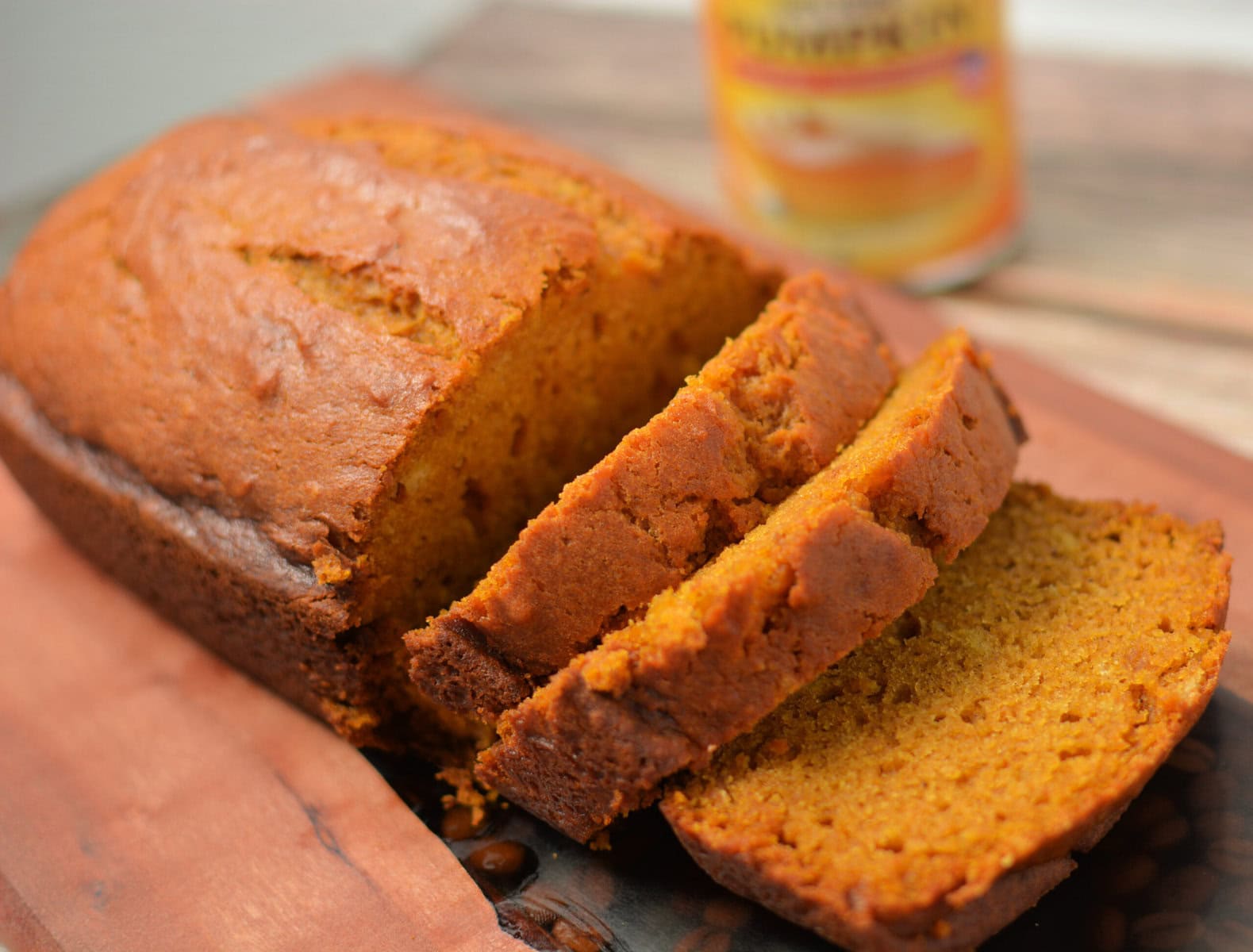pumpkin quick bread sliced on a wood cutting board.