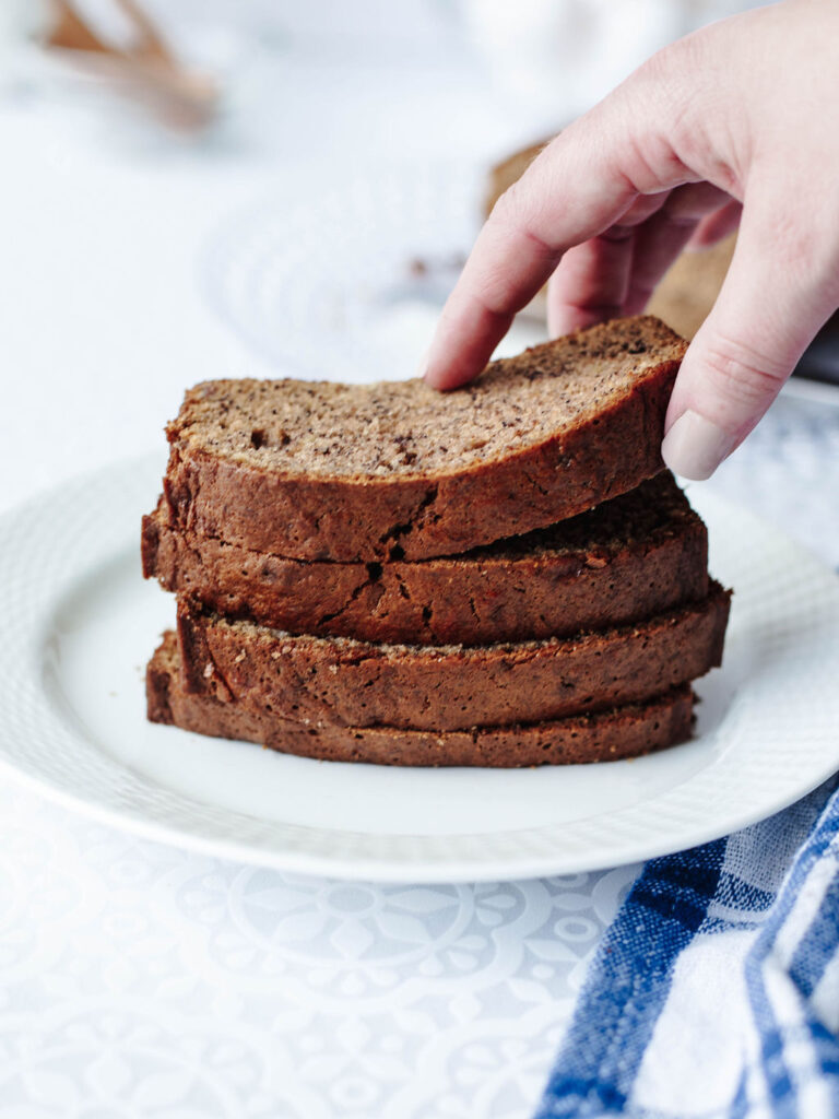 a stack of sliced banana quick bread on a white plate.