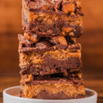 pieces of chocolate peanut butter brownies stacked on a plate.