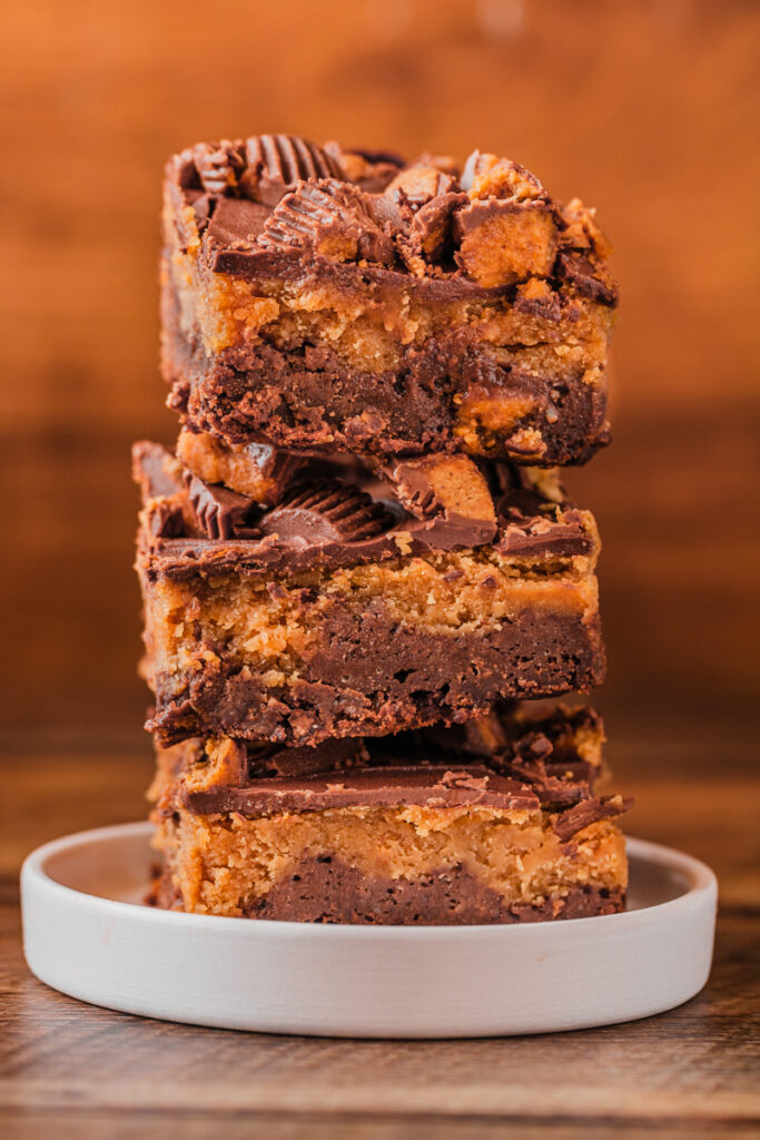 pieces of chocolate peanut butter brownies stacked on a plate.