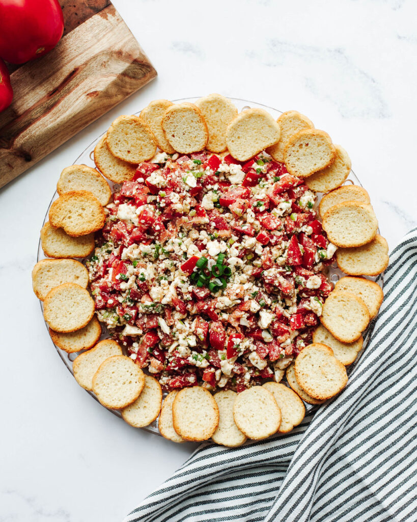 Tomato Feta Dip with toasted baguette bread on a serving platter.