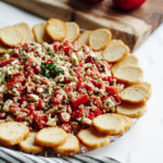 a no bake Mediterranean dip on a glass tray.
