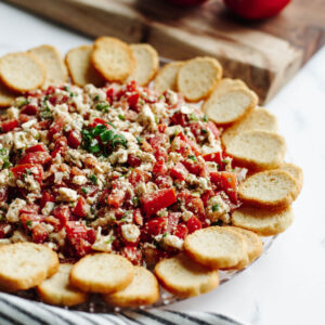 a no bake Mediterranean dip on a glass tray.