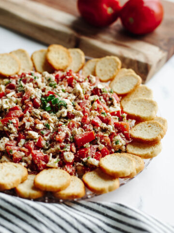 a no bake Mediterranean dip on a glass tray.