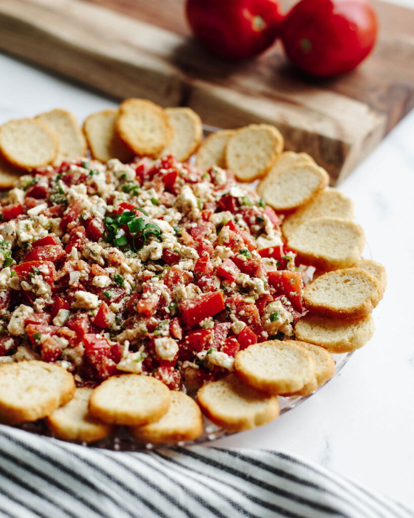 a no bake Mediterranean dip on a glass tray.