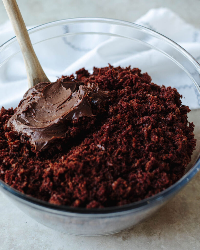 crumbled cake in a glass bowl with chocolate frosting.