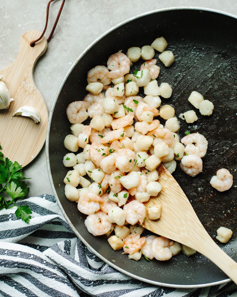 fresh scallops and shrimp in a black skillet.