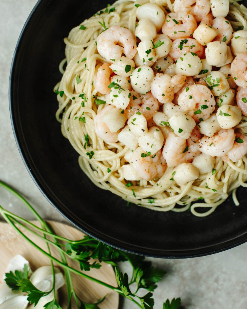 a seafood dinner made with three ingredients over a bed of pasta.