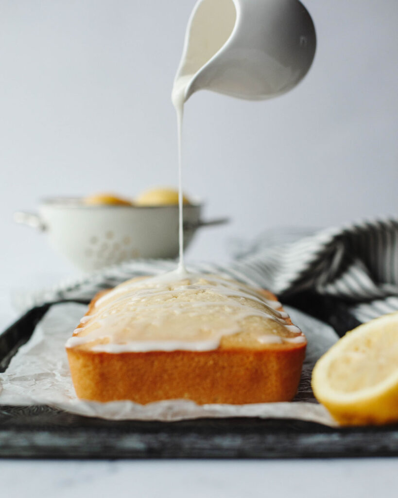 glaze being drizzled over a lemon loaf.