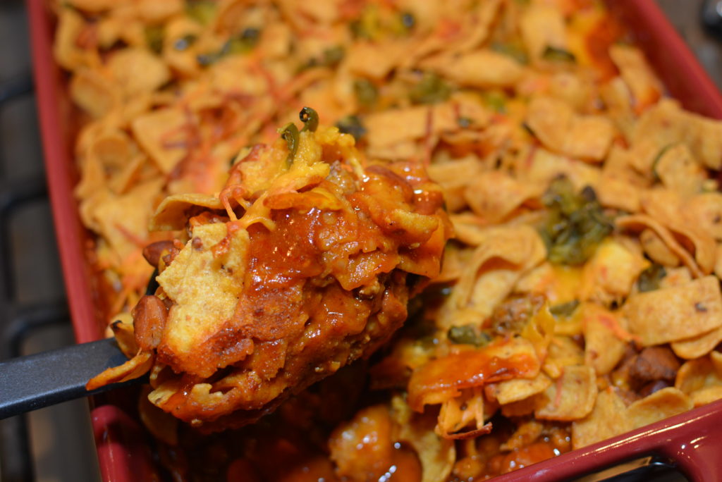 taco chili combined with cheese, toppings, and corn chips