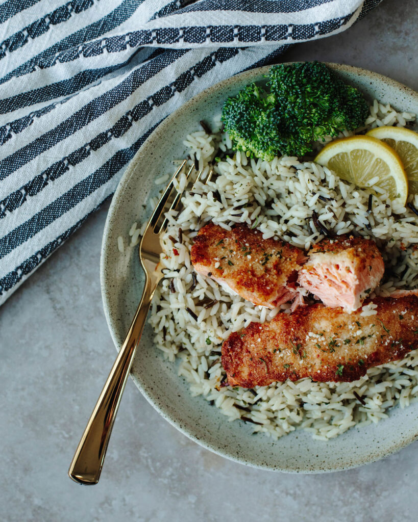 Parmesan crusted salmon that is served over wild rice with broccoli.