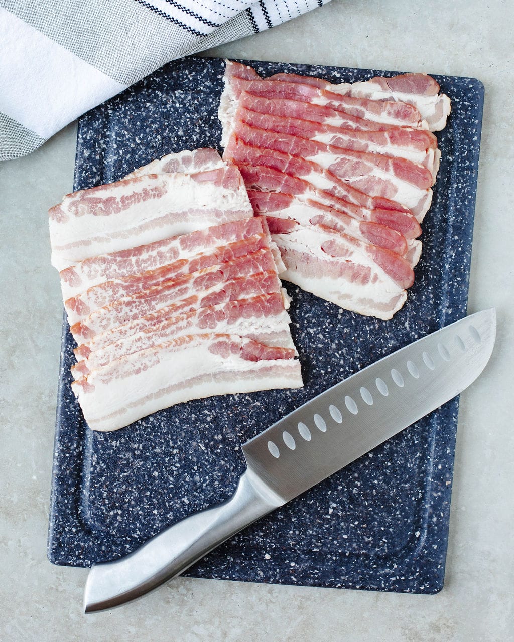 bacon sliced in half on a cutting board.