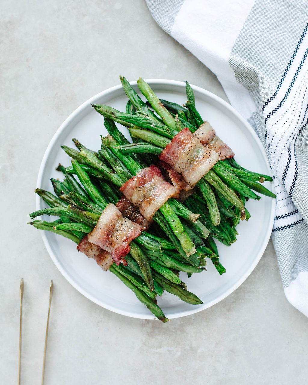 Overhead view of crispy bacon wrapped green bean bundles on a serving plate
