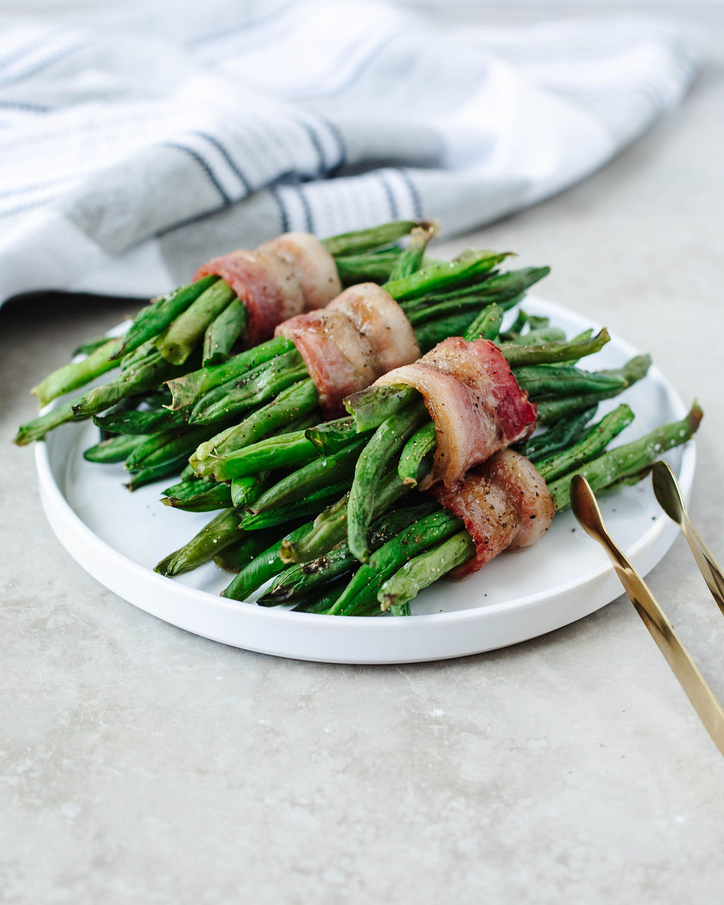 Bacon wrapped green beans served on a white platter as a side dish
